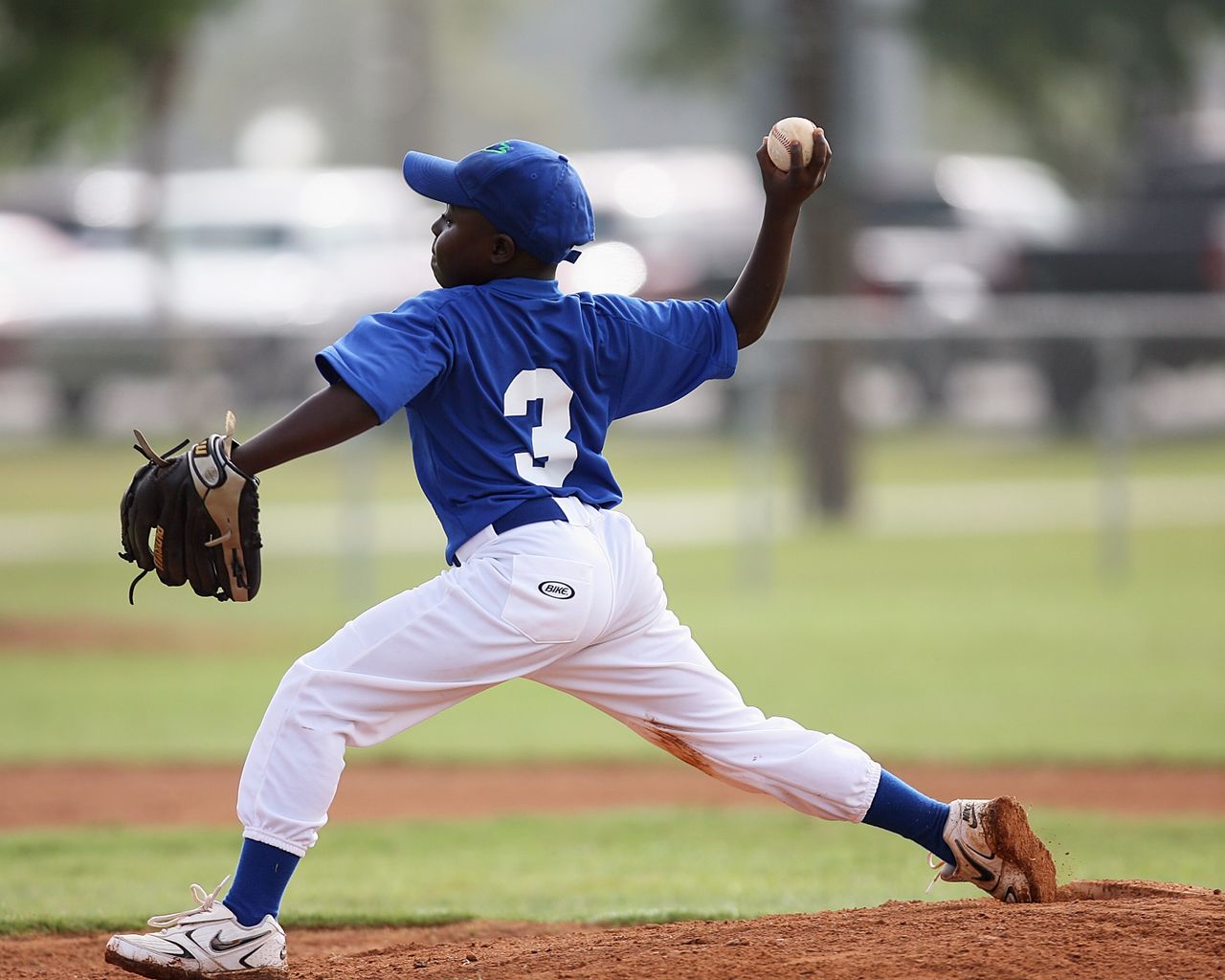 Young player pitching in a youth baseball game on a sunny day.