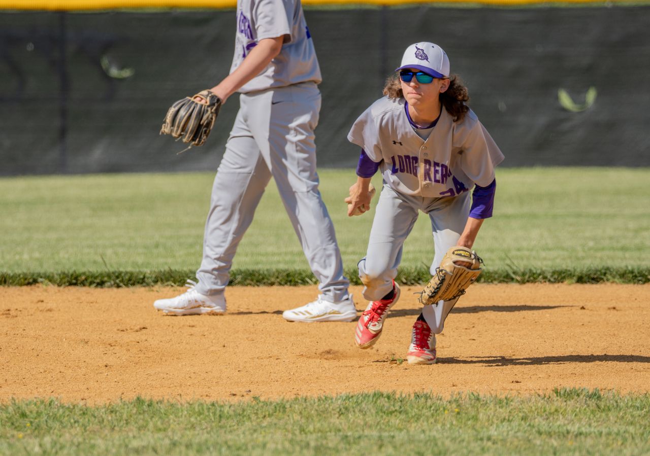 Two teenage baseball players in action on a sunny field in Columbia, MD.